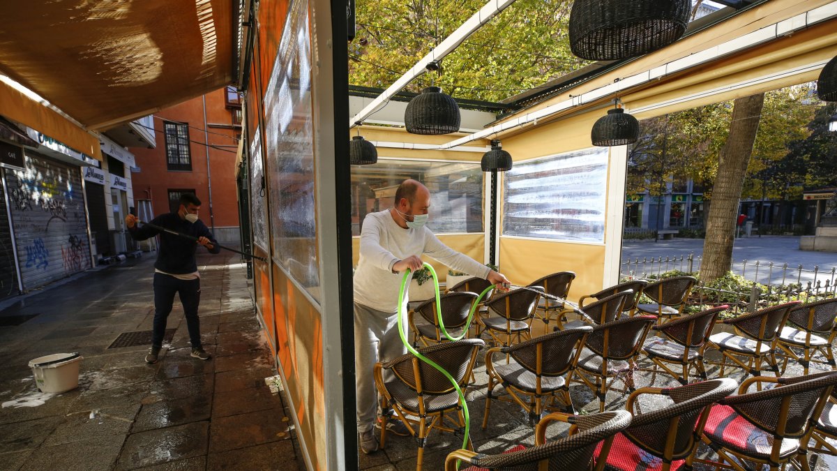 Camareros limpiando y poniendo mesas en una terraza de un bar de Granada.