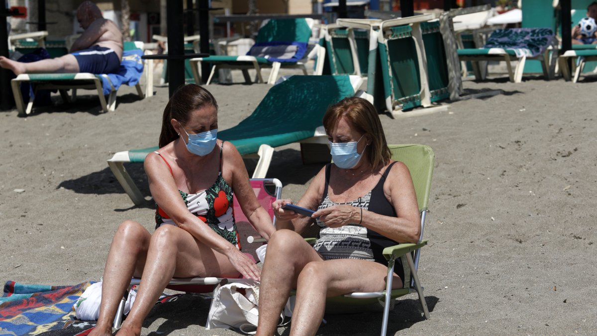 Dos mujeres con mascarillas en la playa de La Malagueta.