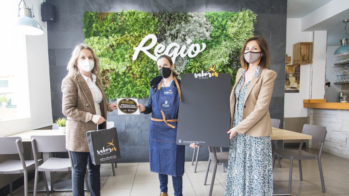 La diputada de Promoción Agroalimentaria, María Luisa Cruz y la concejal de Comercio de Vera, Ana Lourdes Ramírez, entregan material promocional.