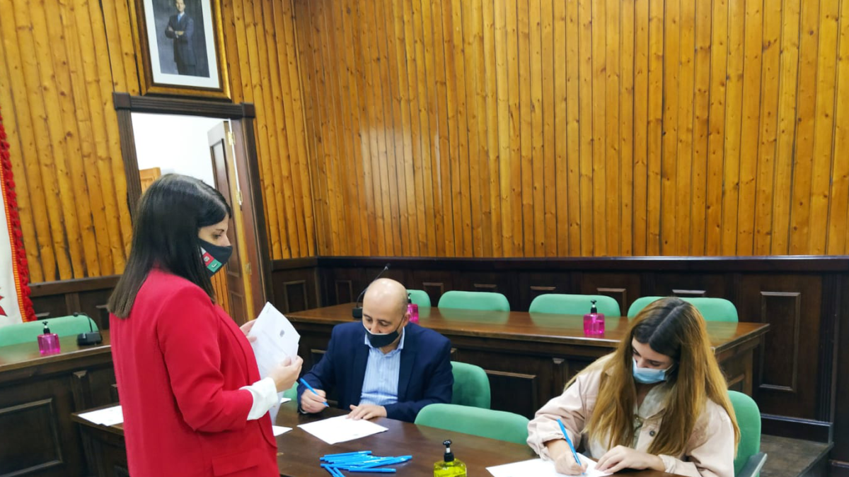 Alcalde y concejal firman el convenio con una de las jóvenes beneficiarias.