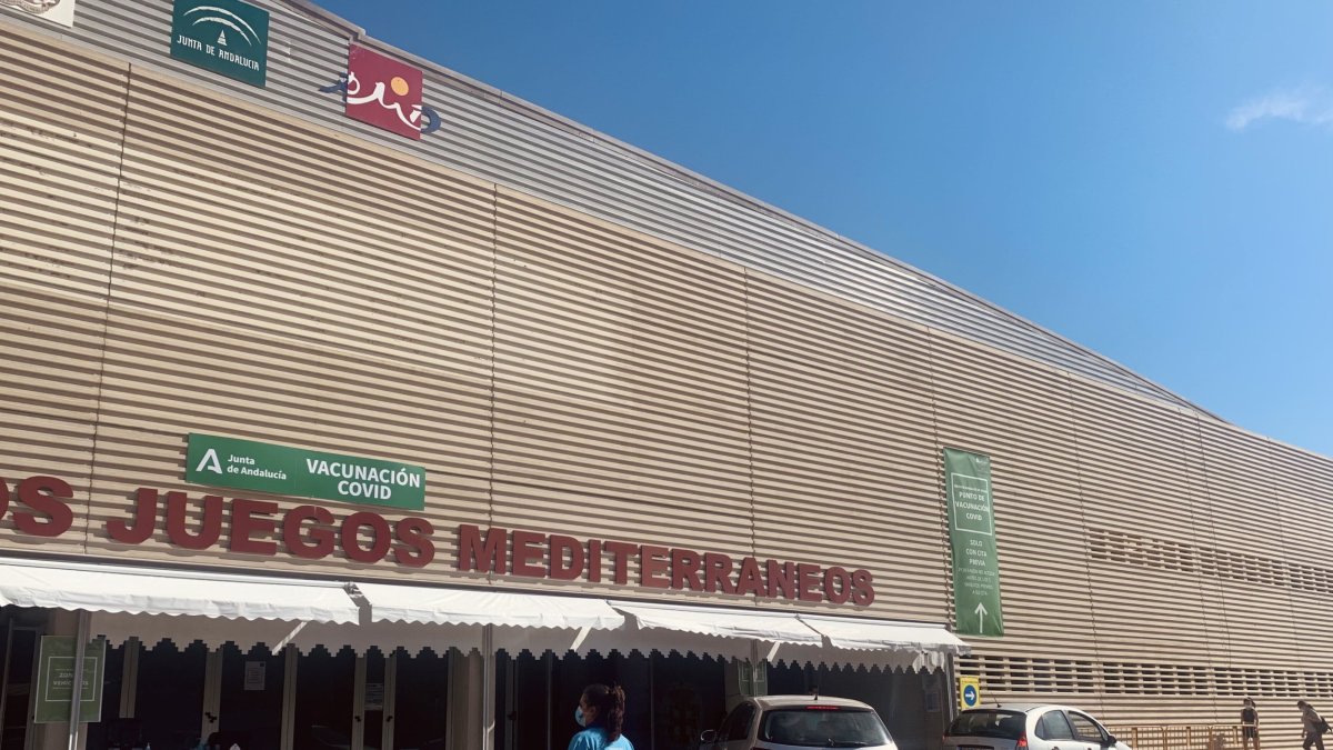 Una sanitaria vuelve a la mesa tras poner una vacuna en el vacunato del Palacio de los Juegos del Mediterráneo
