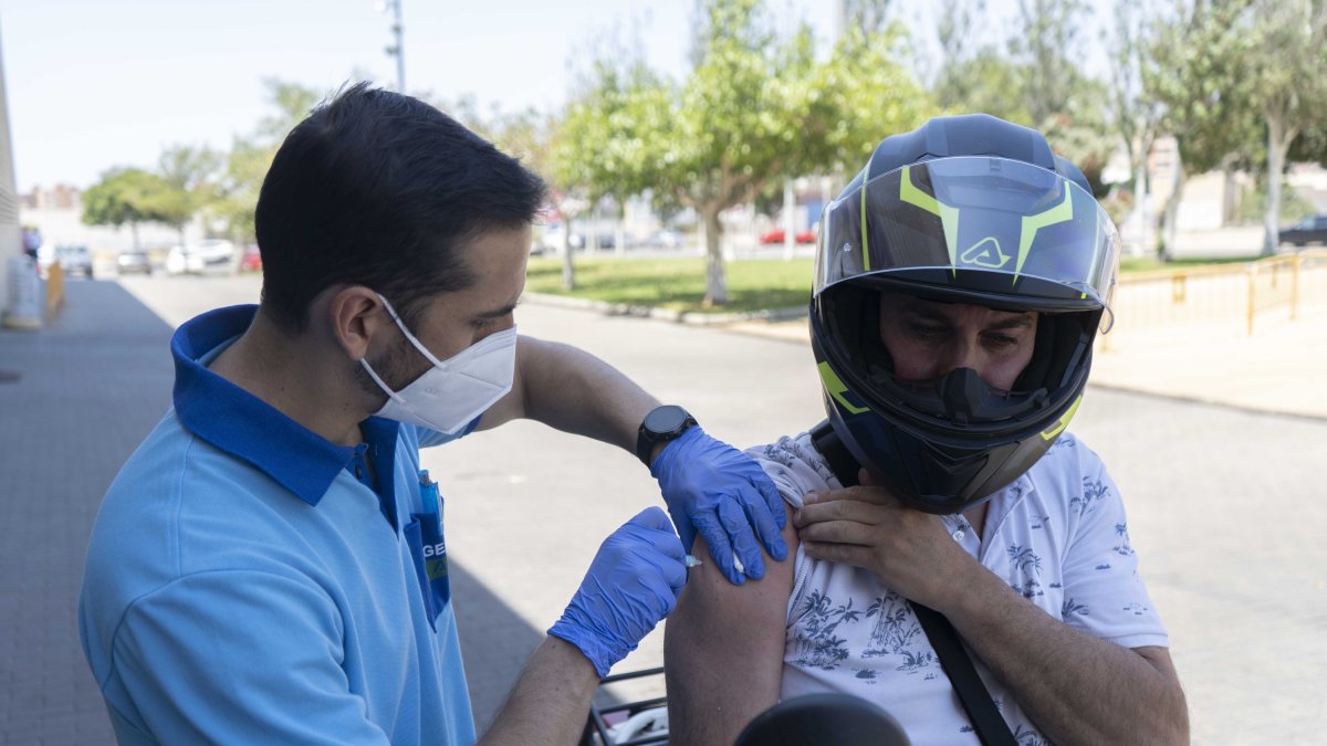 Un hombre es vacunado en su moto en el Palacio de los Juegos Mediterráneos, donde ya puede acudir sin cita cualquier persona mayor de 18 años.