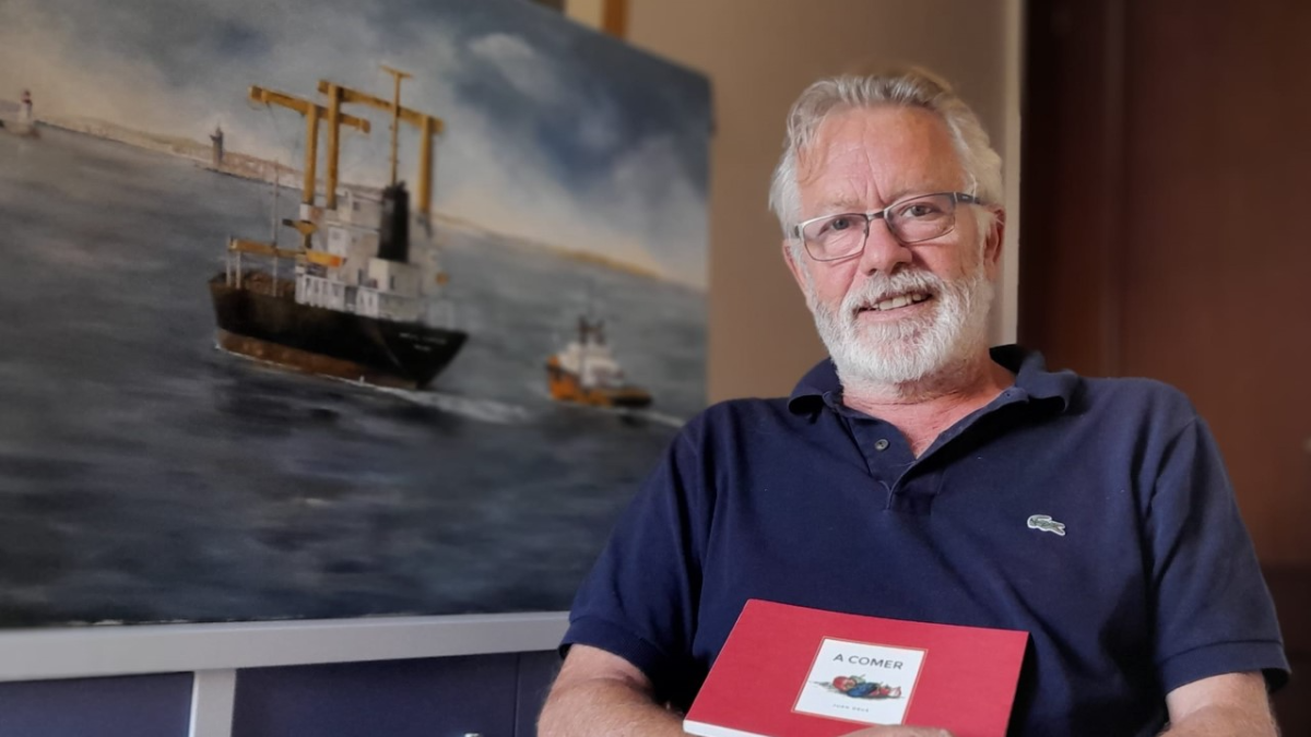 Juan Deus, gallego afincado en Almería, con su libro y junto a la imagen de un barco, un motivo siempre presente en su vida.