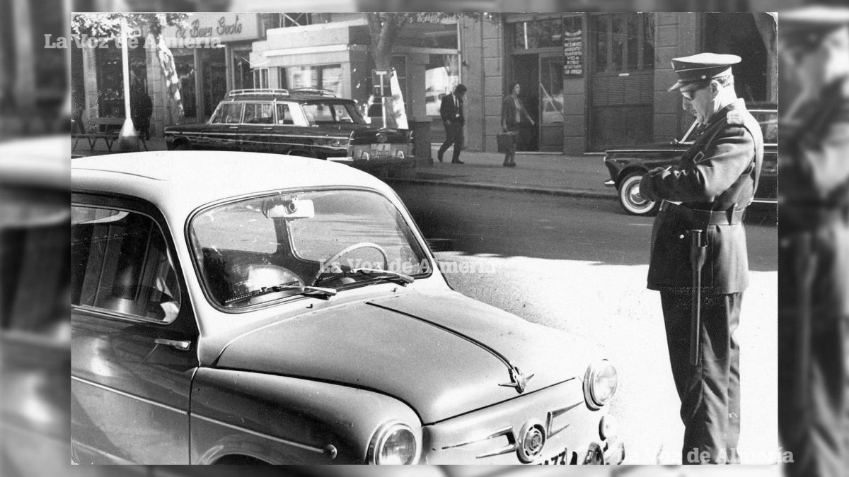 Un policía municipal poniendo un multa por un Seat 600 mal aparcado en el Paseo. Lo habitual era que cada uno dejara el coche en el primer hueco.