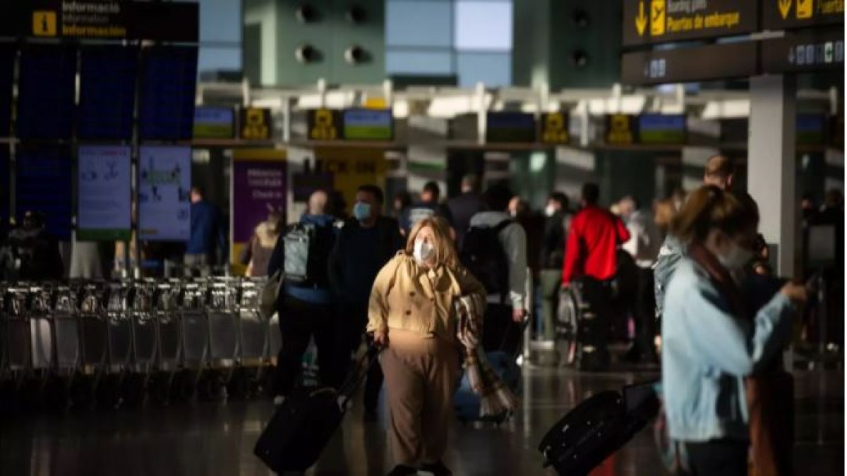 Varios pasajeros con maletas en el aeropuerto de El Prat, en Barcelona.