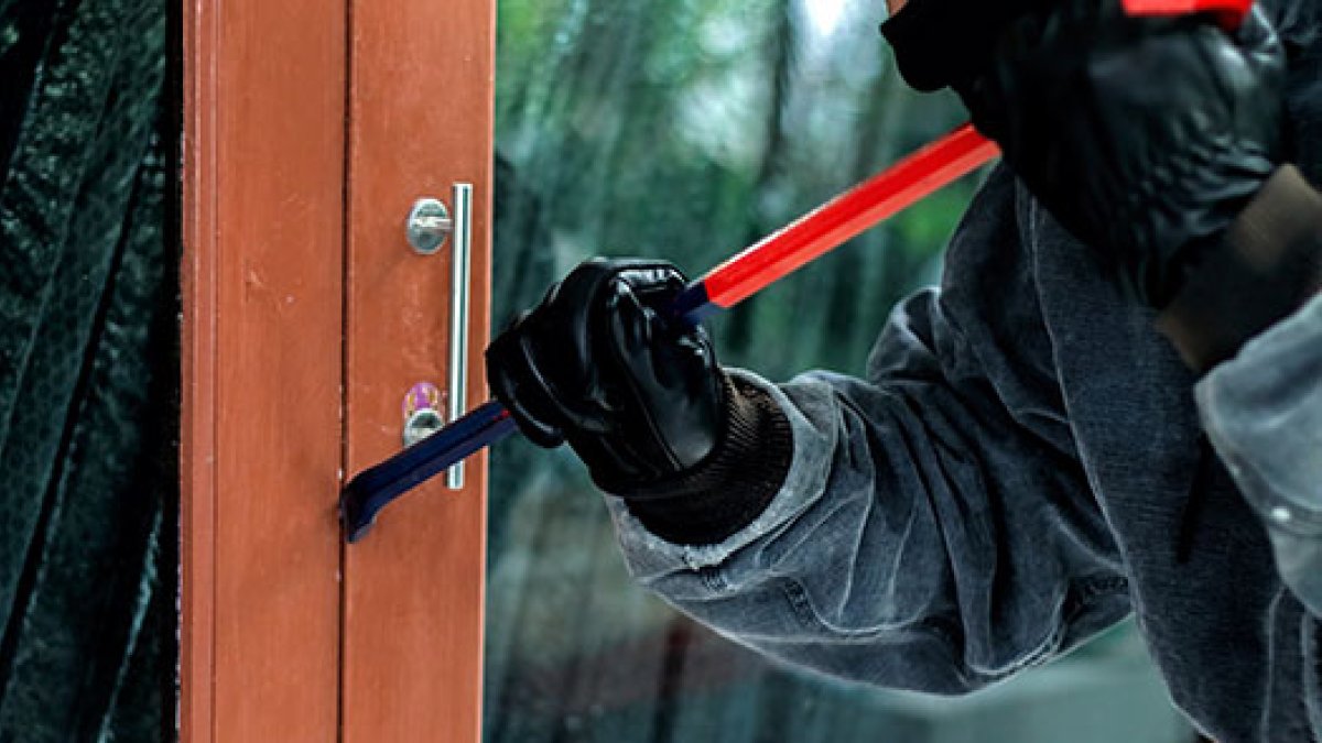 Imagen de un ladrón tratando de forzar una puerta para acceder a una vivienda.
