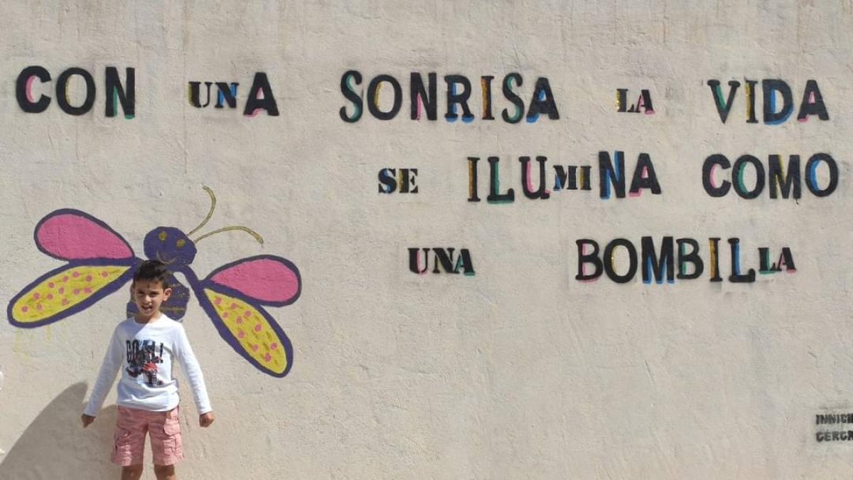 Un crío posa junto a uno de los murales en Gérgal.