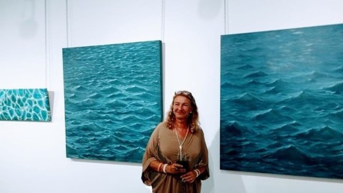 Pamen Merchante junto a una de sus obras expuestas.