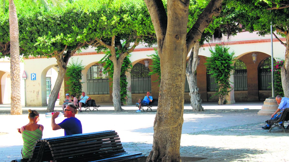 Los turistas y los vecinos que pasan por la Plaza Vieja buscan el refugio de los bancos bajo la sombra de los árboles.