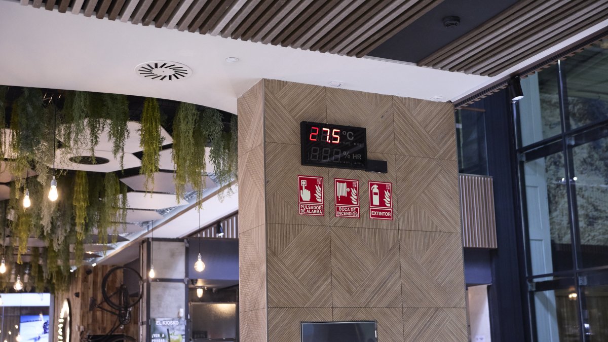 Un termómetro marca 27,5 grados de temperatura junto al restaurante de un centro comercial.