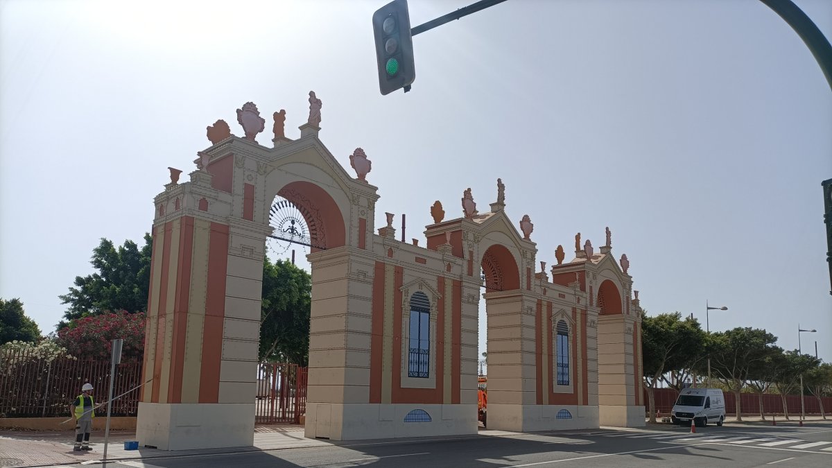 Un operario repinta la portada de la feria de la noche