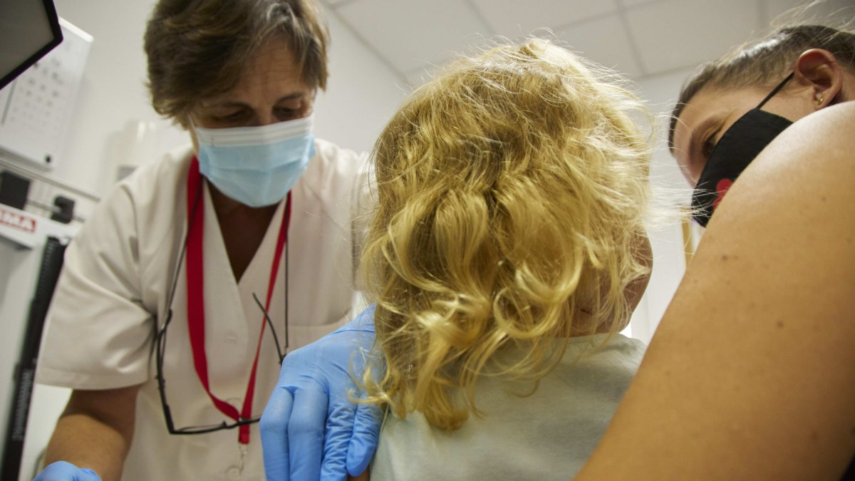 Una enfermera vacuna de la gripe a una niña.