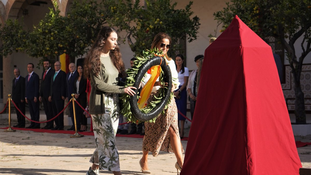La alumna Ana Segura coloca la corona de flores junto a su profesora