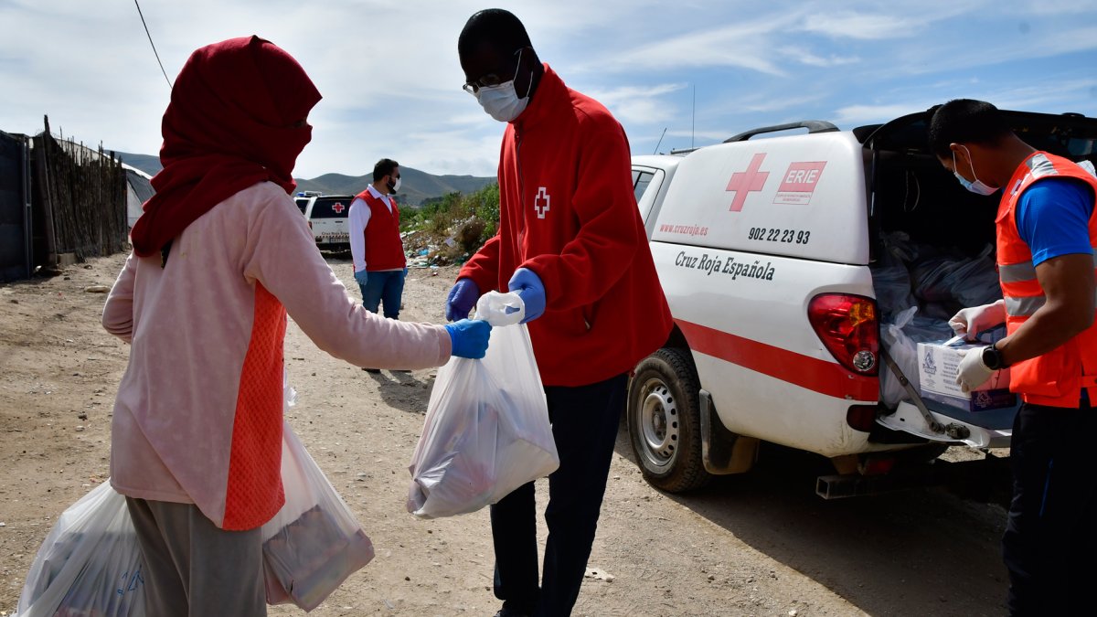 Un voluntario de Cruz Roja entrega productos de primera necesidad en un asentamiento de la provincia de Almería