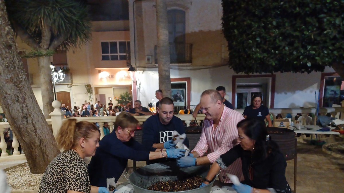 Los voluntarios y el alcalde rellenan cucuruchos de castañas para los vecinos.