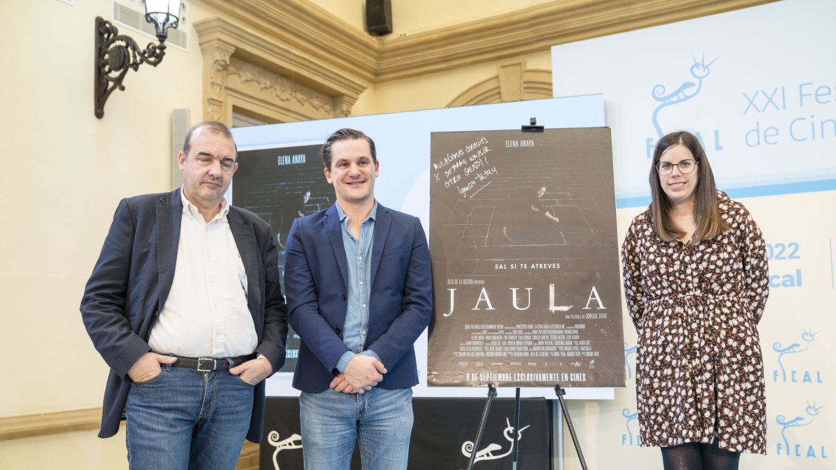 Ignacio Tatay, director de Jaula, con Enrique Iznaola y Almudena Morales frente al póster de su película.