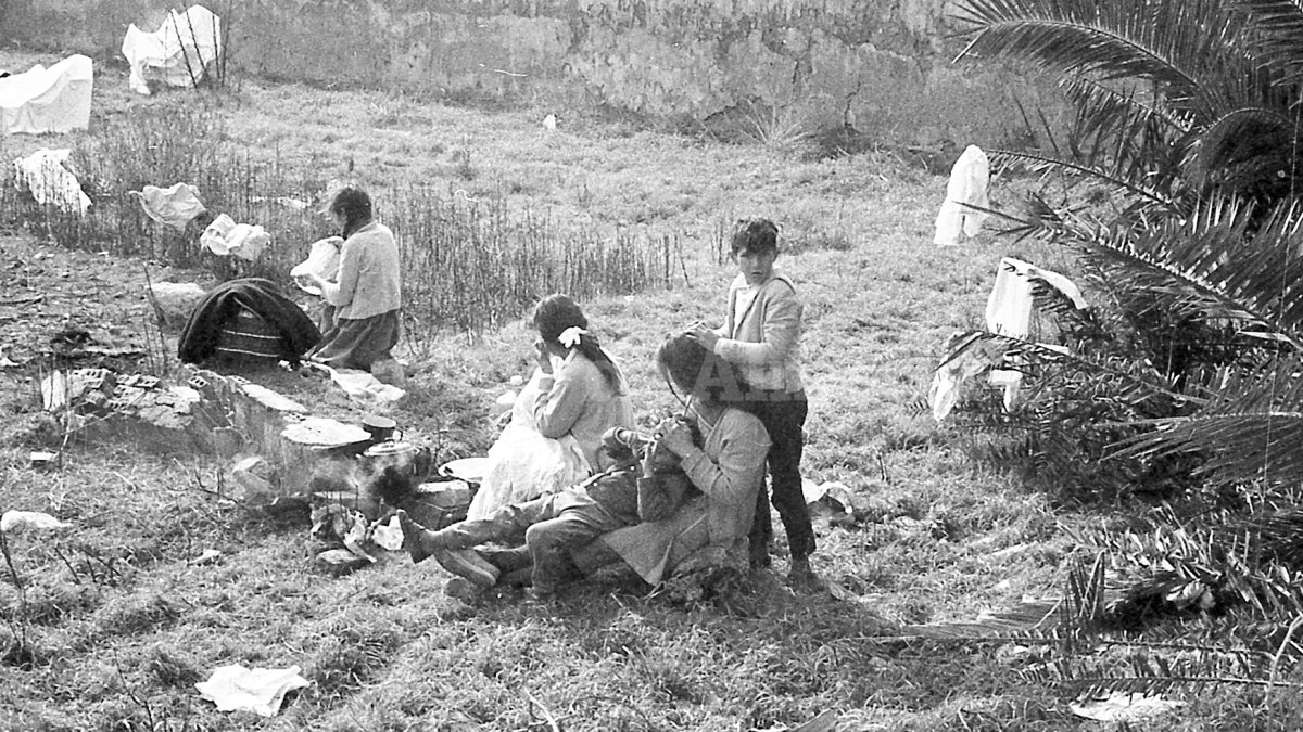 Una madre repasa la cabeza de su hijo mientras el hermano mayor repasa a su vez la cabeza de la madre buscando la presencia de parásitos, en 1970.