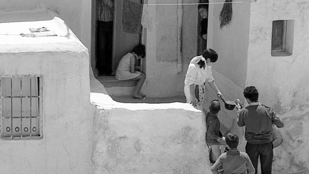 Un lechero llenando el cazo de una clienta en el barrio de la Chanca allá por los años sesenta.
