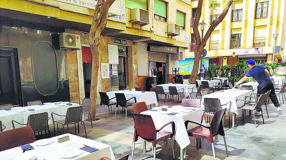 Un camarero, preparando las mesas, todas reservadas, del bar Sacromonte, en la Plaza de Vivas Pérez.