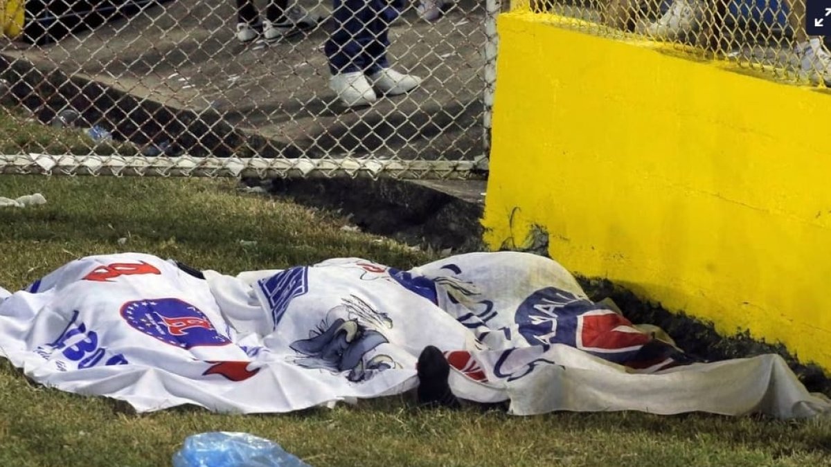 Una manta cubre varios cadáveres sobre el césped del Estadio Cuscatlán. / MILTON FLORES