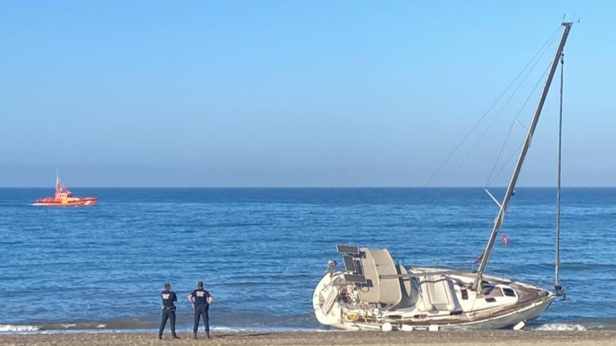 Agentes de la Policía Local de El Ejido junto al velero varado en Almerimar.