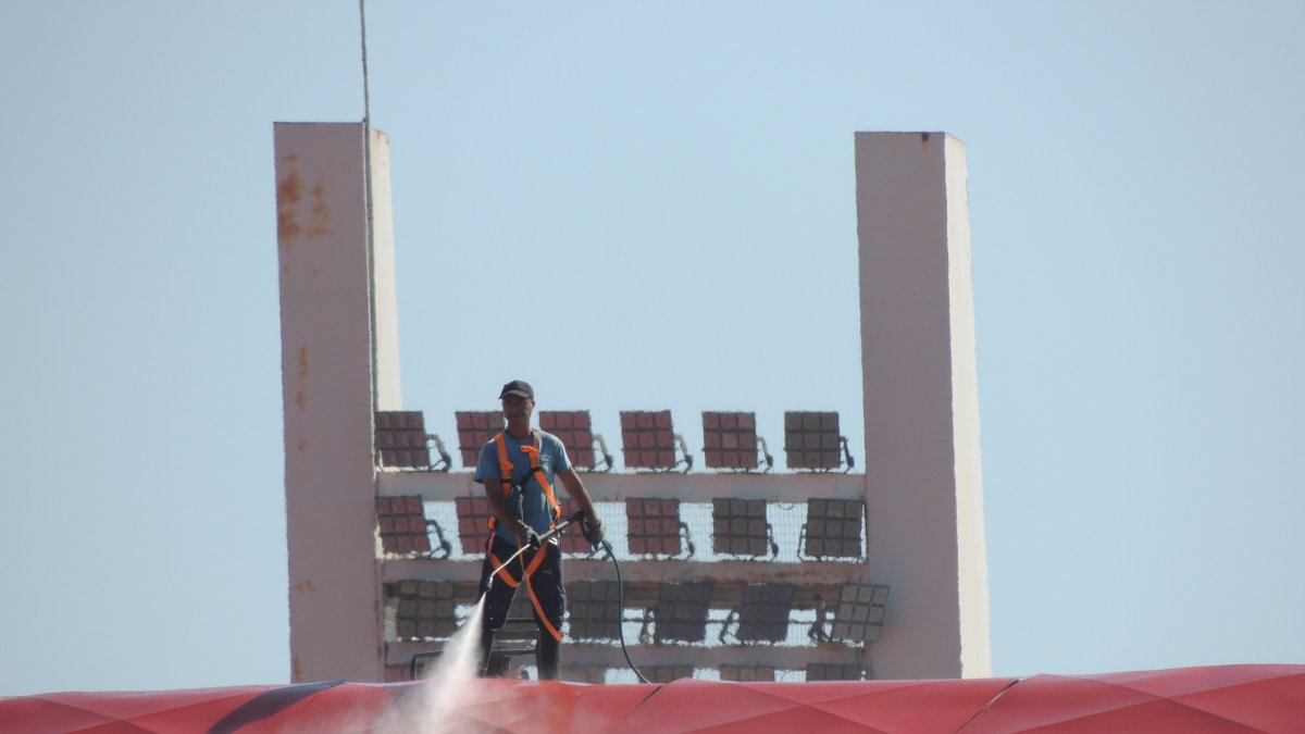 Un operario limpiando con agua a presión la cubierta de tribuna.