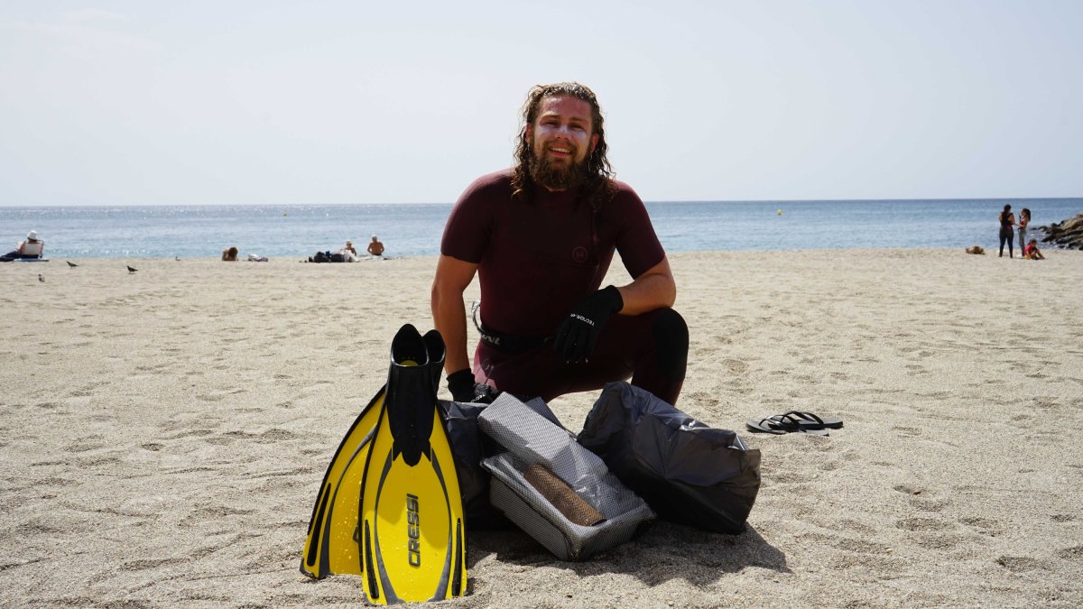 Damián Reyes posa sobre la arena de la playa con varias bolsas llenas de residuos que acaba de sacar del mar en El Zapillo.
