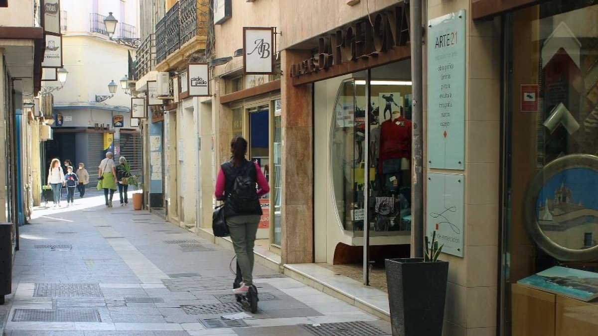 Una joven en patinete por una calle peatonal