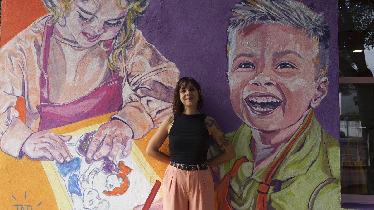 La artista Tati Salvador posa en uno de los murales que ha pintado en la fachada de su centro \'Tu Arte lo Parte\'.