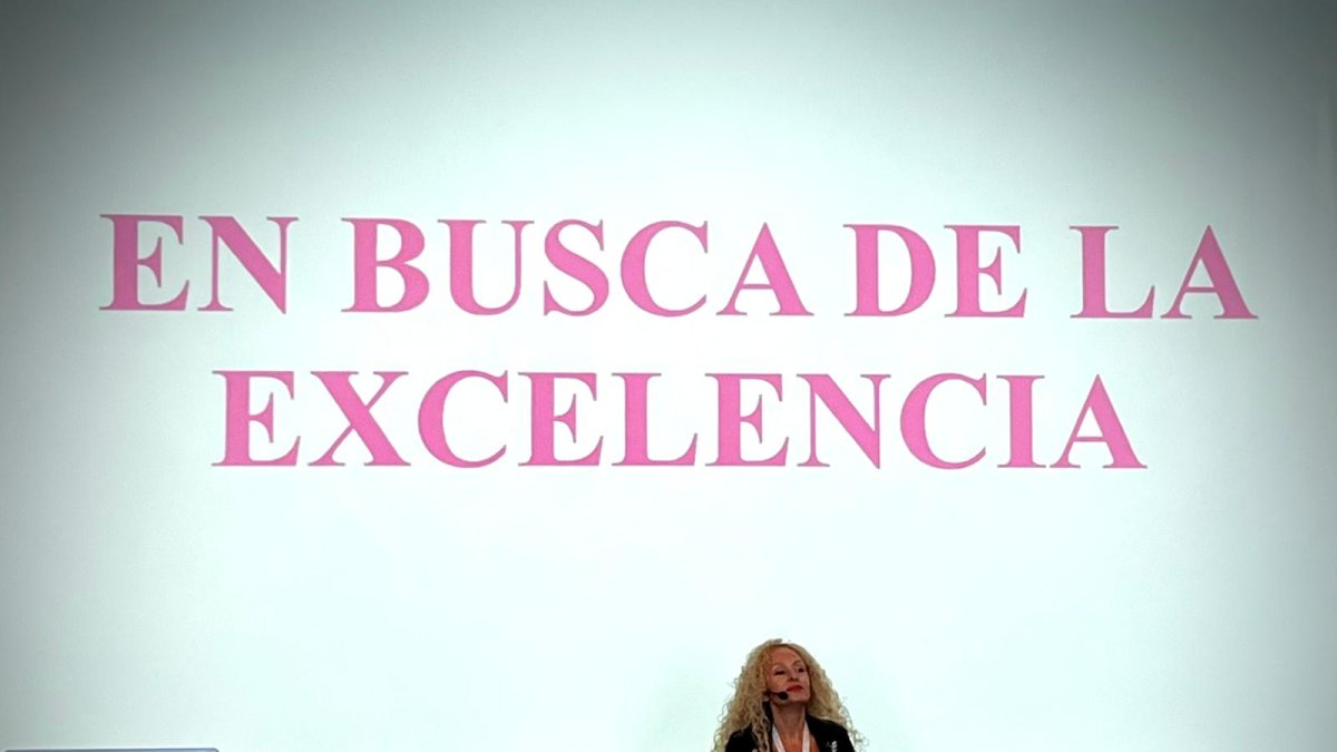 Conchi impartiendo una conferencia con su lema detrás.