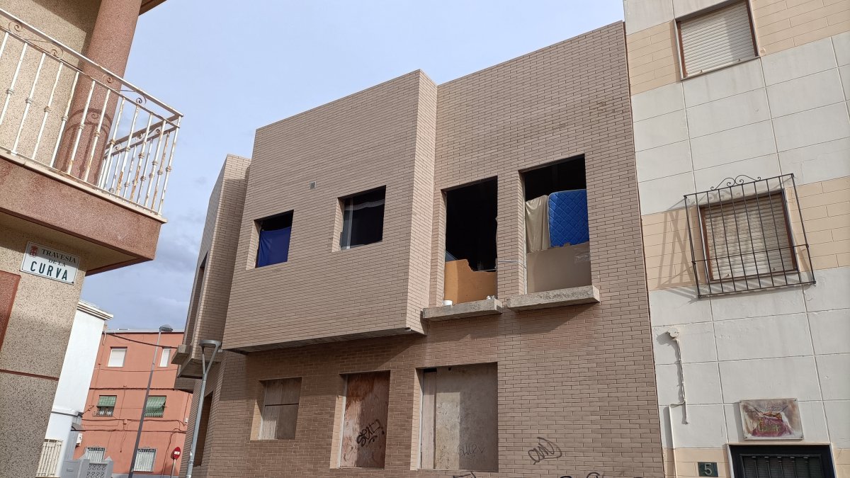 Por las ventanas de la primera planta se ve calzado, mantas y colchones.