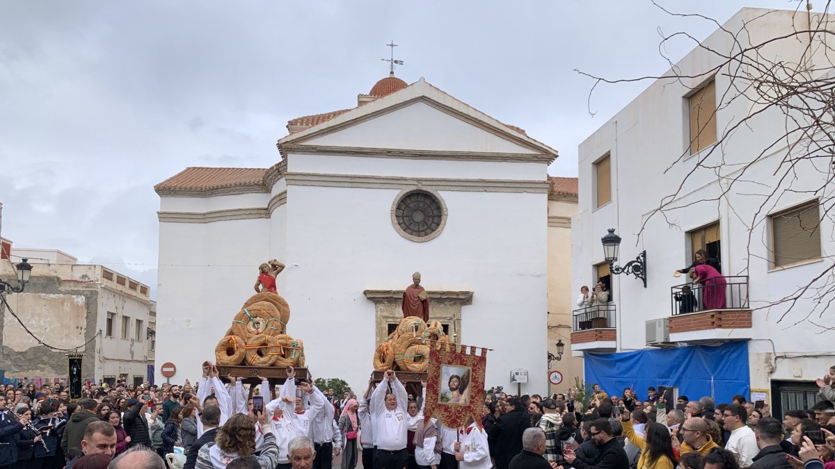 Los costaleros levantan los santos al cielo antes de comenzar la procesión de la lluvia de pan.