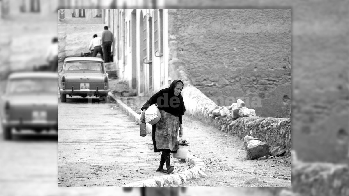 Una mujer vestida de luto, con el mandil de la colada, por la calle de la Salud del barrio de La Chanca a finales de los años 60.