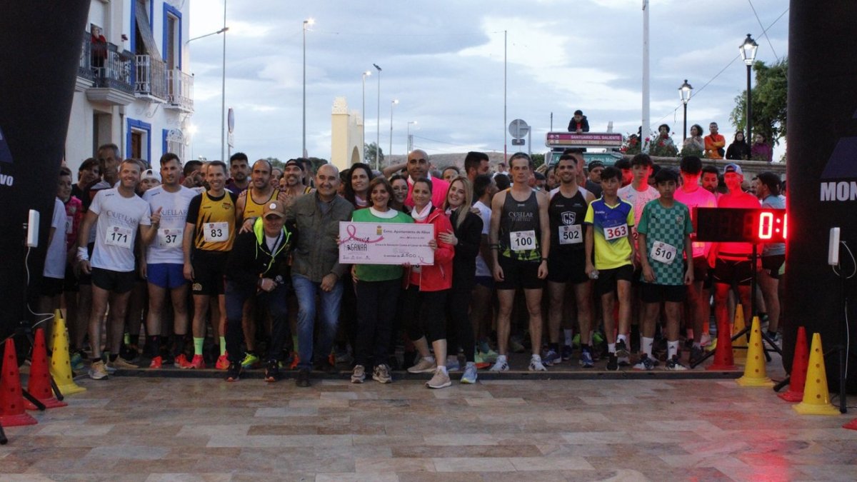 Autoridades, corredor y miembros de la AECC con el chuque de la donación.