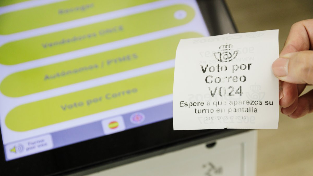 Una persona con un ticket de voto por correo en la oficina de Correos.
