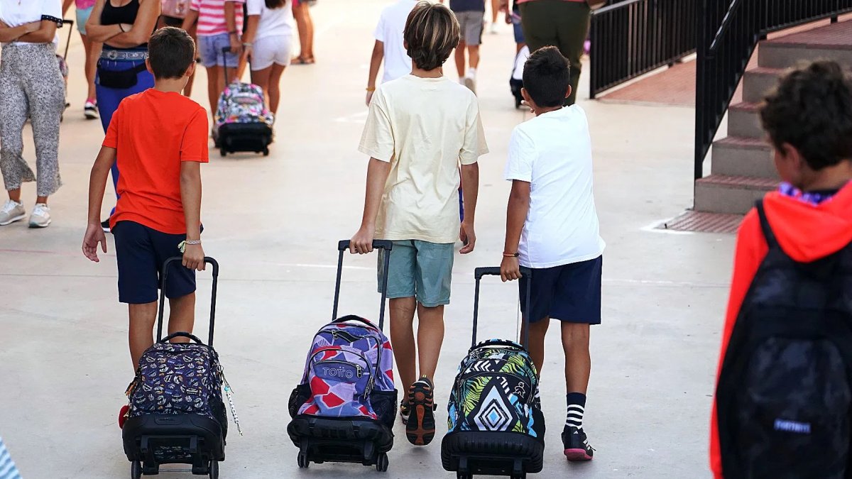 Imagen de archivo de niños llegando al colegio con sus mochilas.