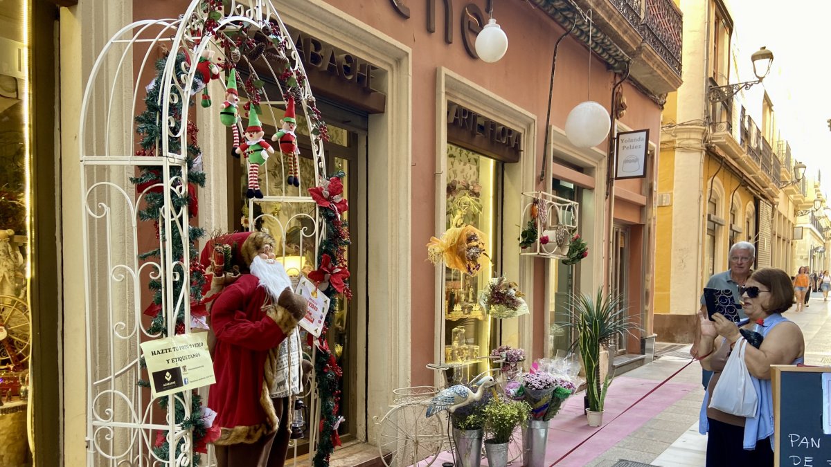 Una mujer echa una fotografía al Papá Noel de la Floristería Azabache, local que desde principios de agosto ha colocado su avance de Navidad.
