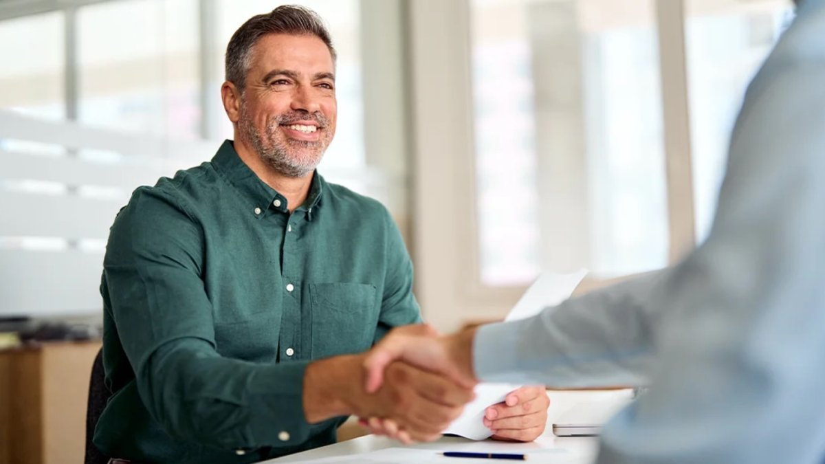 Un trabajador da la mano a otra persona.
