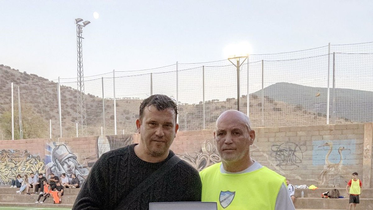 El presidente de la peña y el padre de la fallecida posando con una placa en honor a Leticia.