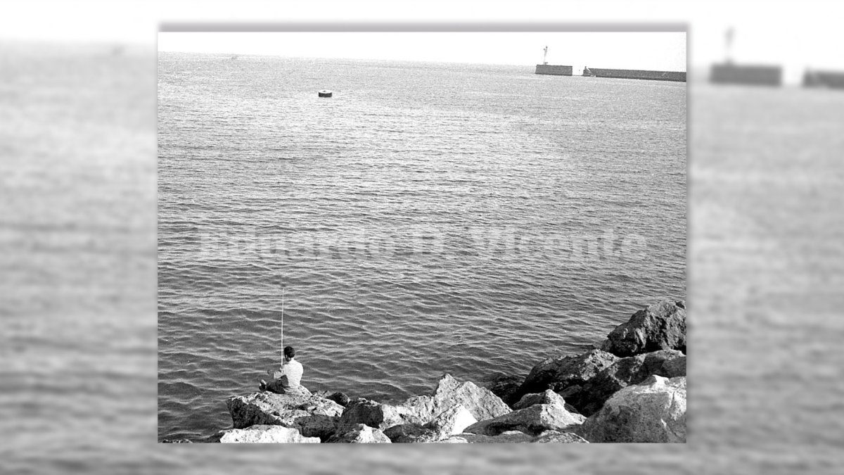 Rocas del espigón de levante, lugar de niños y pescadores, con la boya y el Faro al fondo.