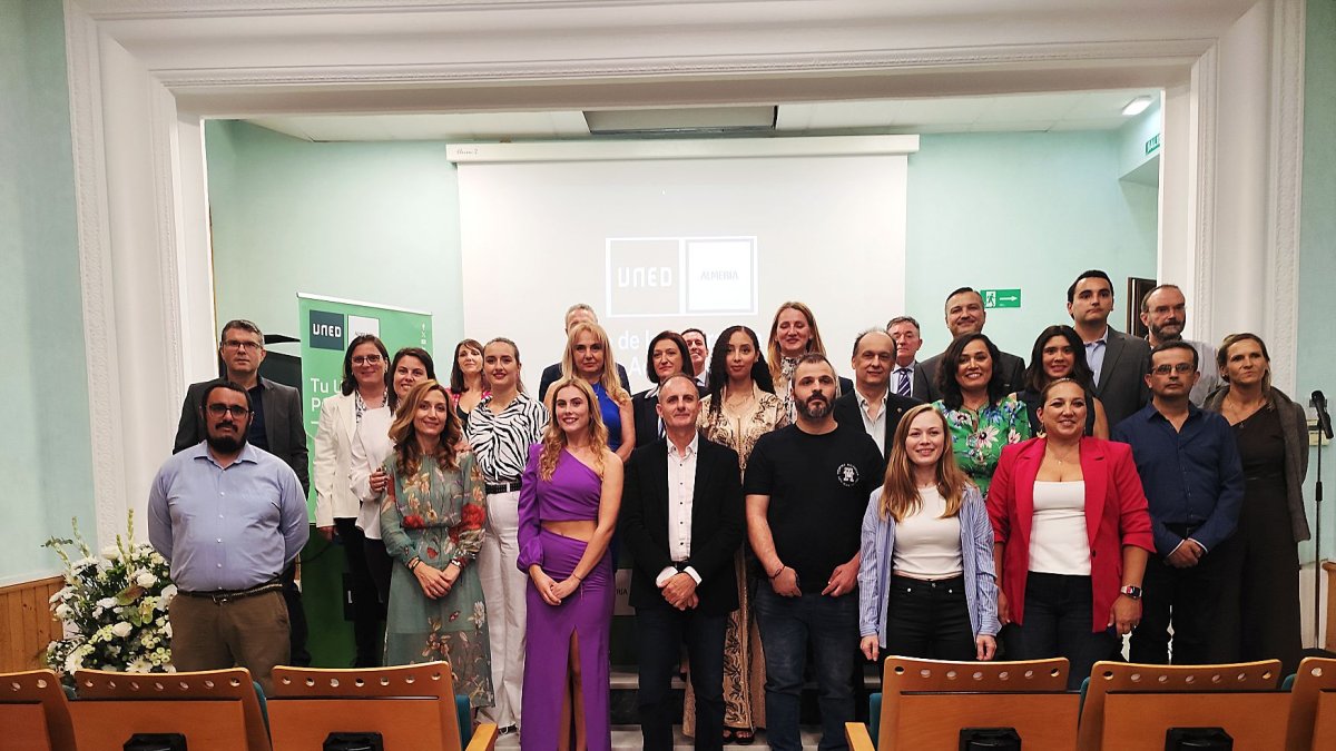 Foto de familia de los alumnos graduados junto a los miembros de la mesa inaugural.