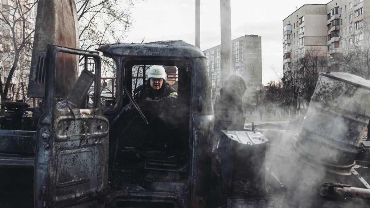Un bombero se asoma por la ventana de un vehículo militar del ejército ucraniano calcinado.