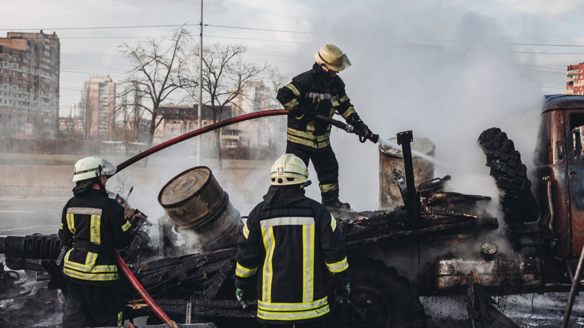 Varios bomberos apagan el fuego de un vehículo militar del ejército ucraniano.