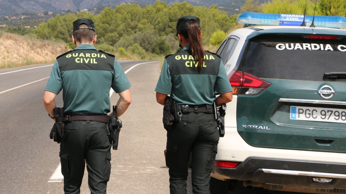 Dos agentes de la Guardia Civil montan guardia en una carretera.