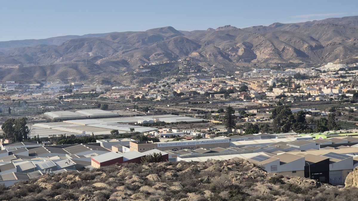 El primer plano las naves del polÍgono con la sierra al fondo.