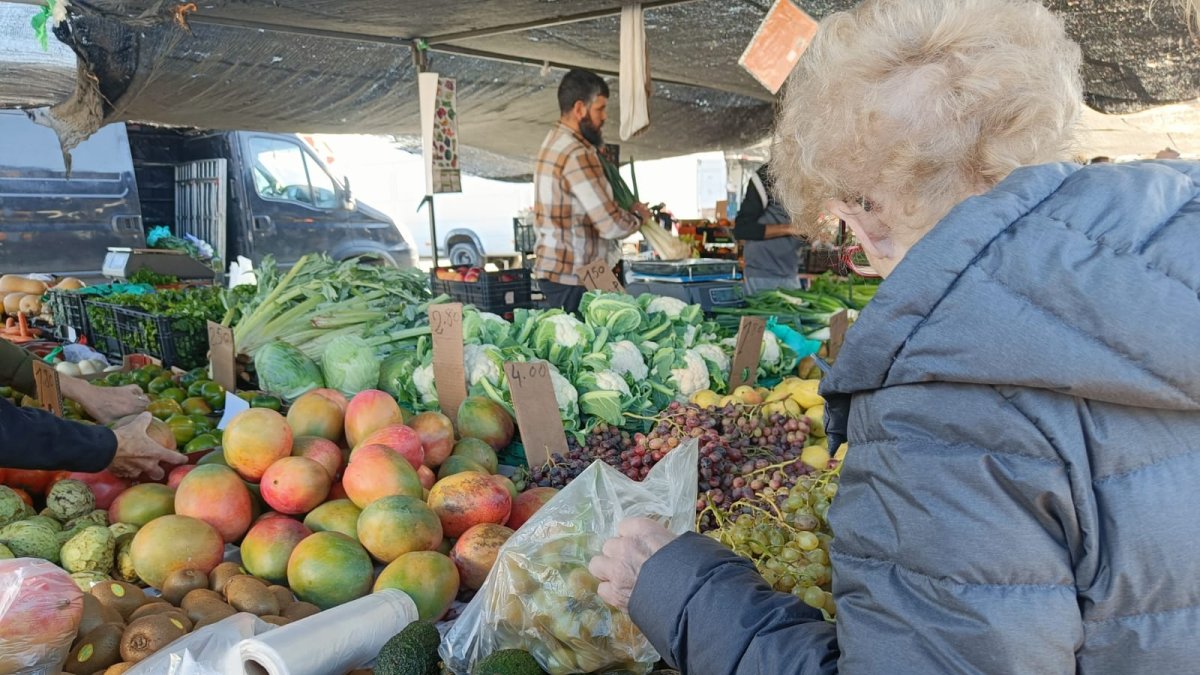 Una clienta observa uvas en el mercadillo de El Zapillo.