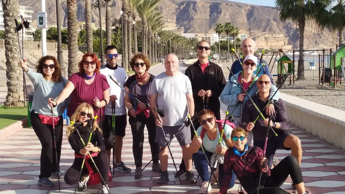 Sentada en el suelo Marcela Alonzúa con sus alumnos de Marcha Nórdica Club al Sol.