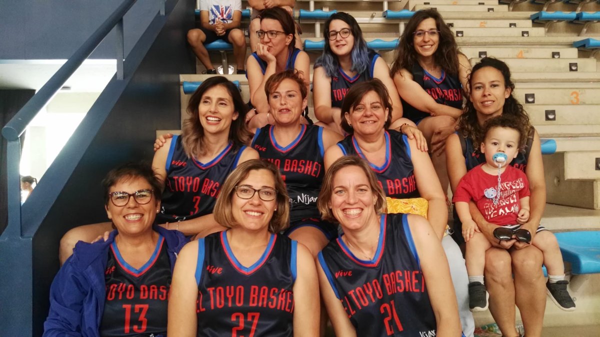 El equipo senior femenino de El Toyo Basket en la grada, esperando para empezar un partido.