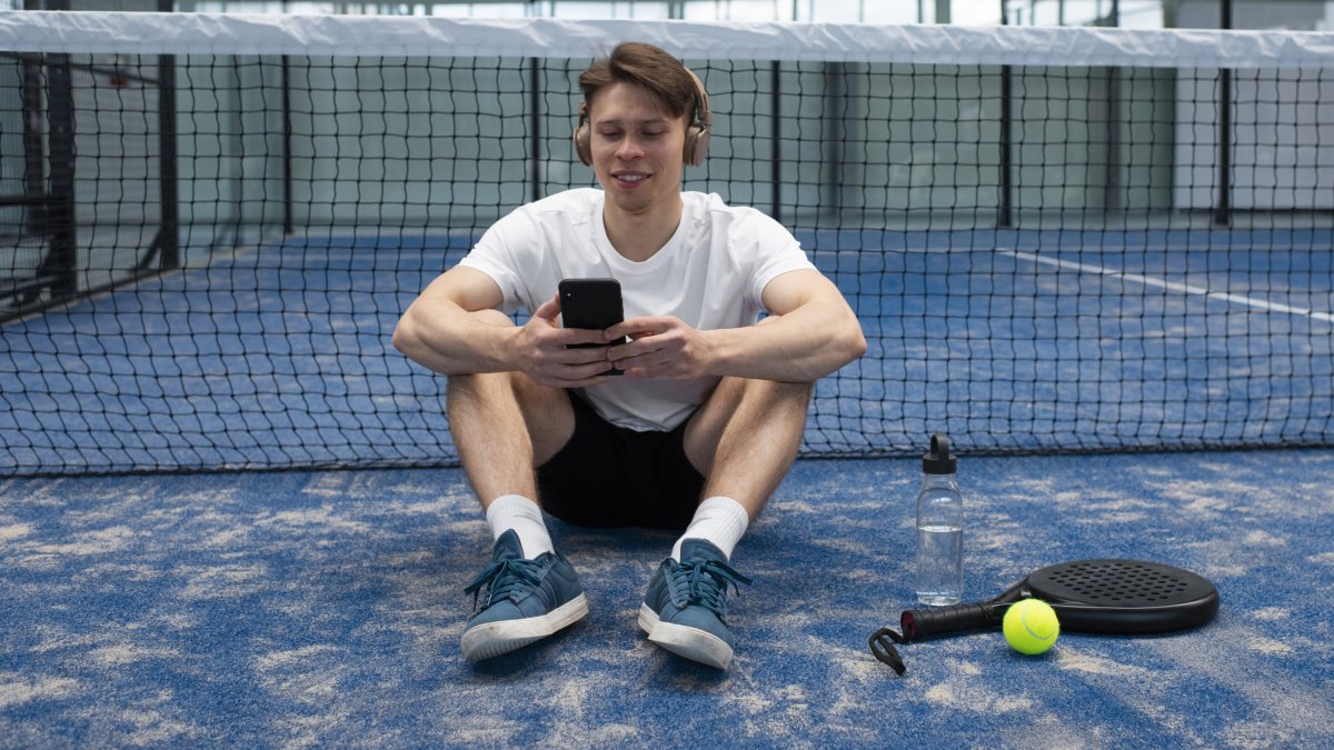 Una persona mira su teléfono móvil en una pista de pádel.