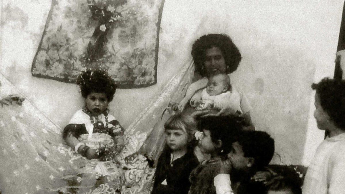 Niña vestida de maya en La Chanca, en una imagen de Pérez Siquier. La rodea su madre y una cohorte de niñas.